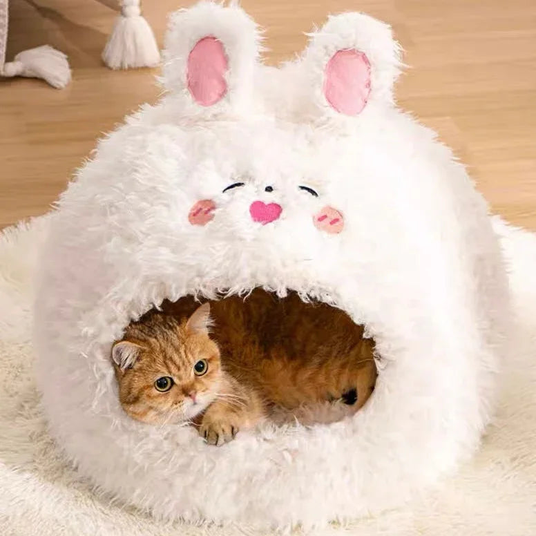 Cat peeking out from a fluffy white pet house with bunny ears and face.
