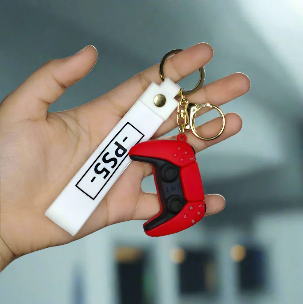 Hand holding a keychain with a red PS5 and white tag against a gray tiled wall.