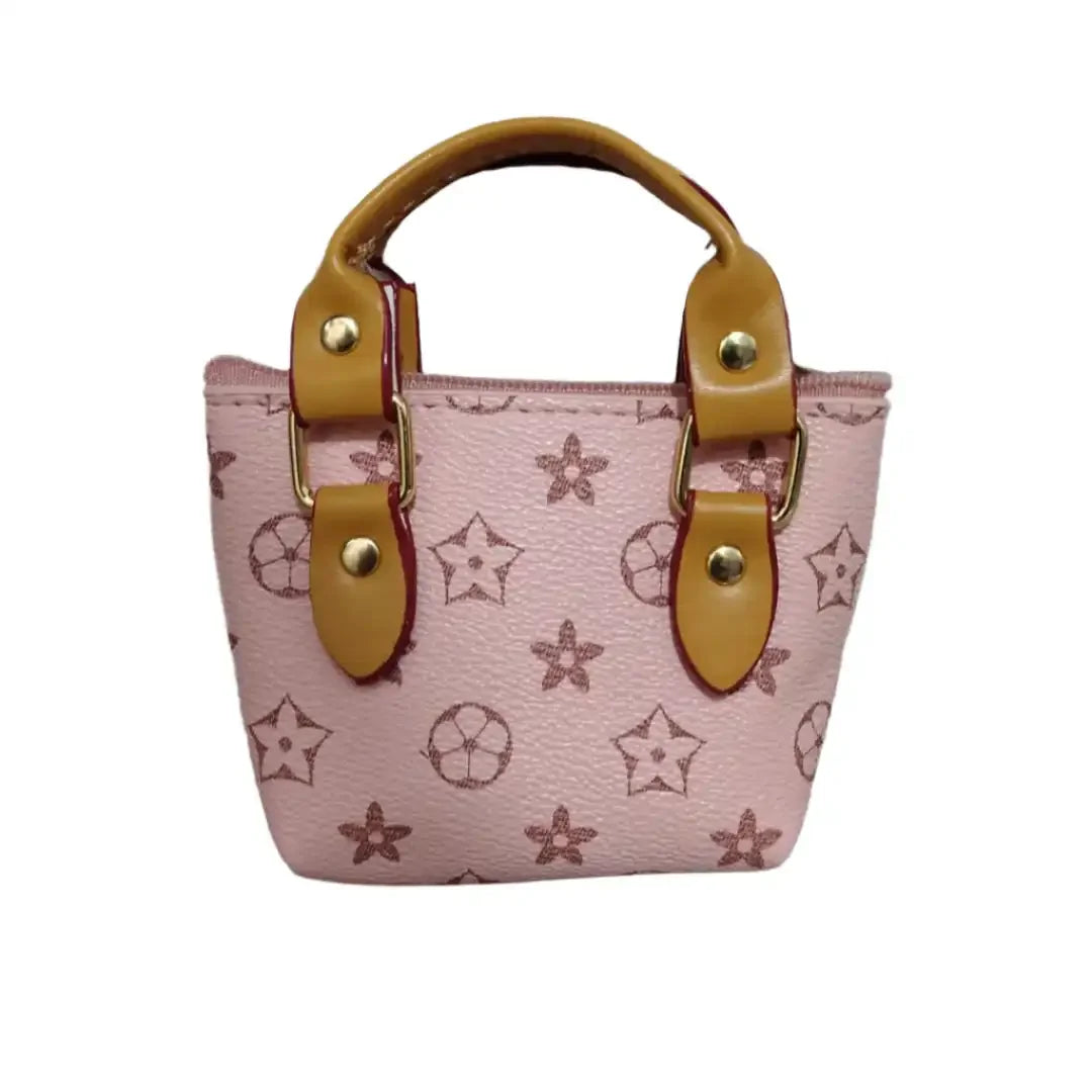 Pink handbag with star pattern and brown handles on a textured surface