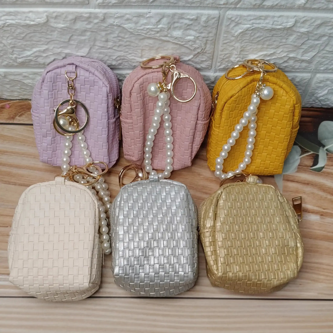 Set of six small pouches in different colors with keychains on a wooden surface.