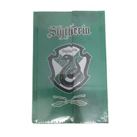 Green notebook with 'Slytherin' emblem on a gray concrete surface