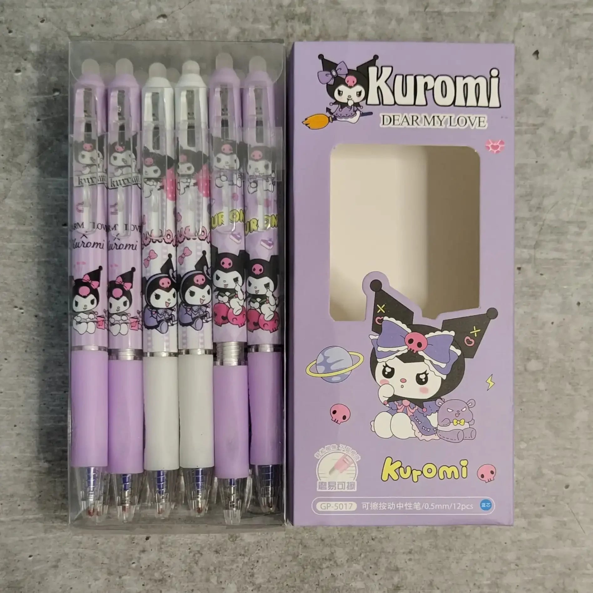 Set of purple and white pens with packaging featuring a character named 'Kuroni' on a gray concrete background.
