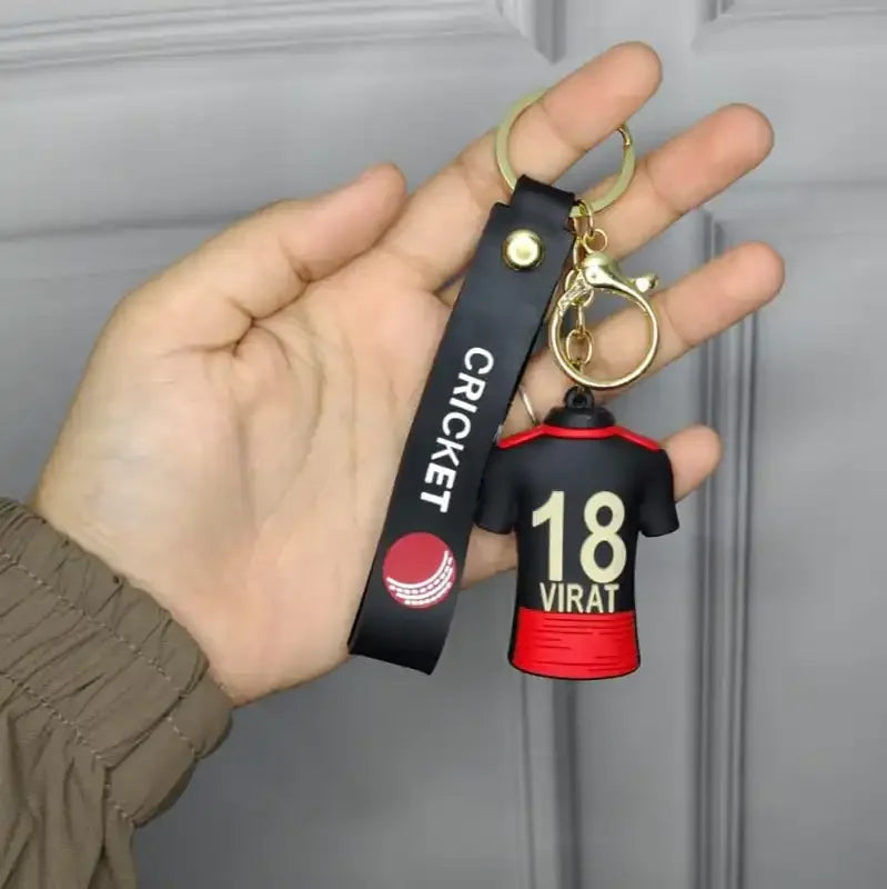 Keychain with virat kohli jersey design held by a hand against a neutral background