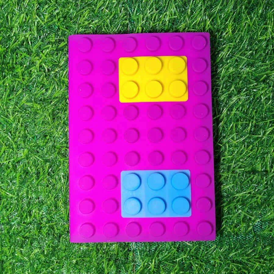 Pink building block diary with yellow and blue bricks on grass