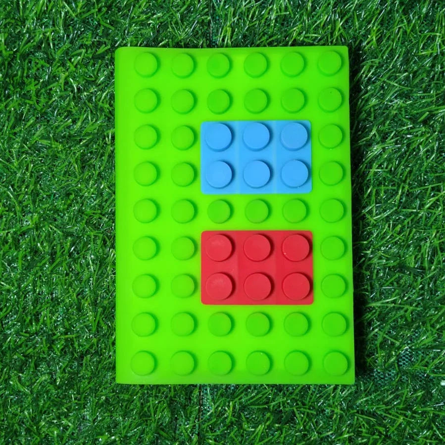Green building block notebook with blue and red blocks on a grass background