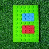 Green building block notebook with blue and red blocks on a grass background