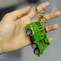 Hand holding a green toy truck keychain against a gray background