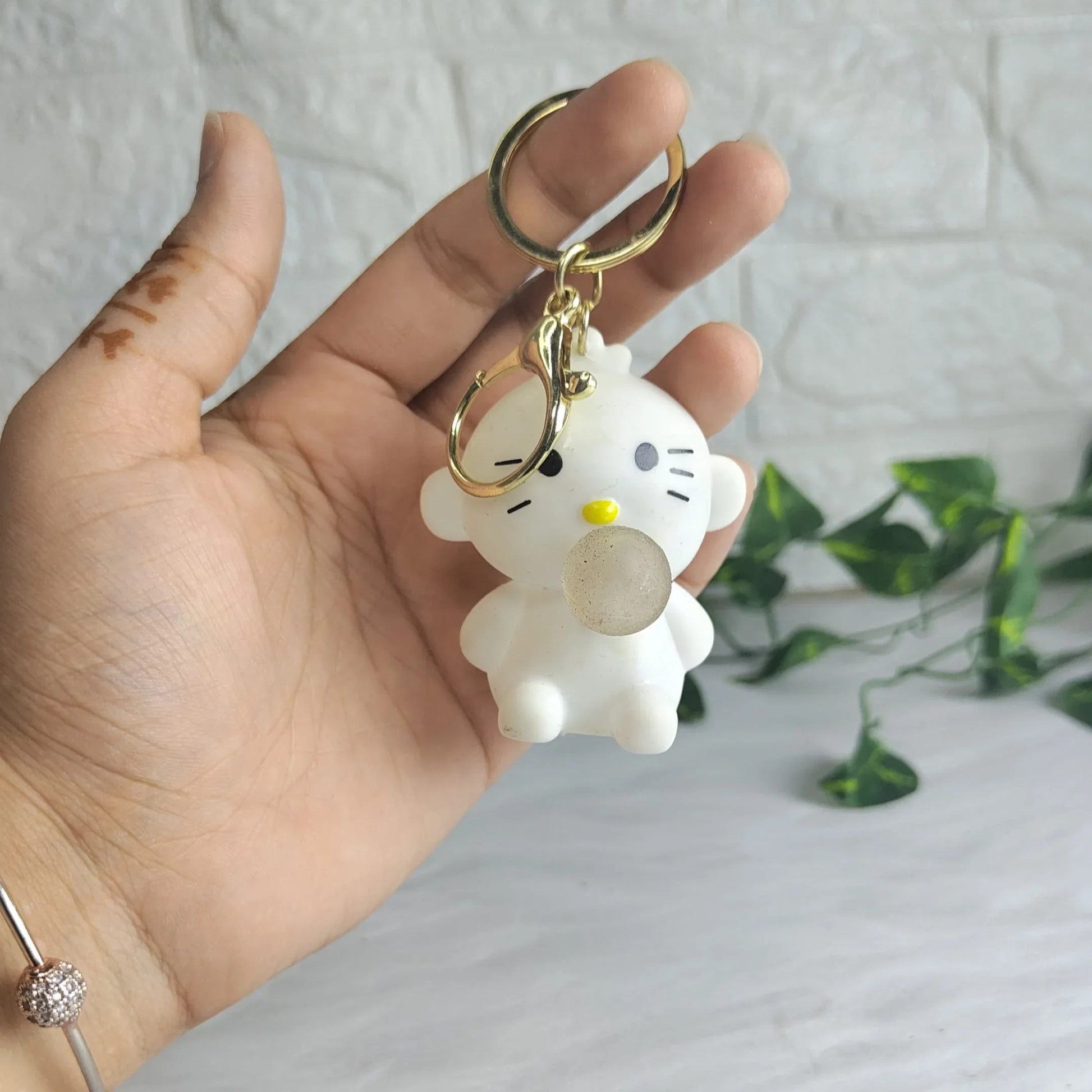 Hand holding a keychain with a cartoon character against a light gray background
