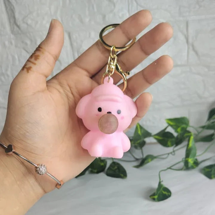 Pink bear-shaped keychain held in a hand with a light gray background