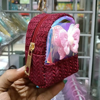 Red glittery pouch with a bow keychain held in a hand against a blurred background