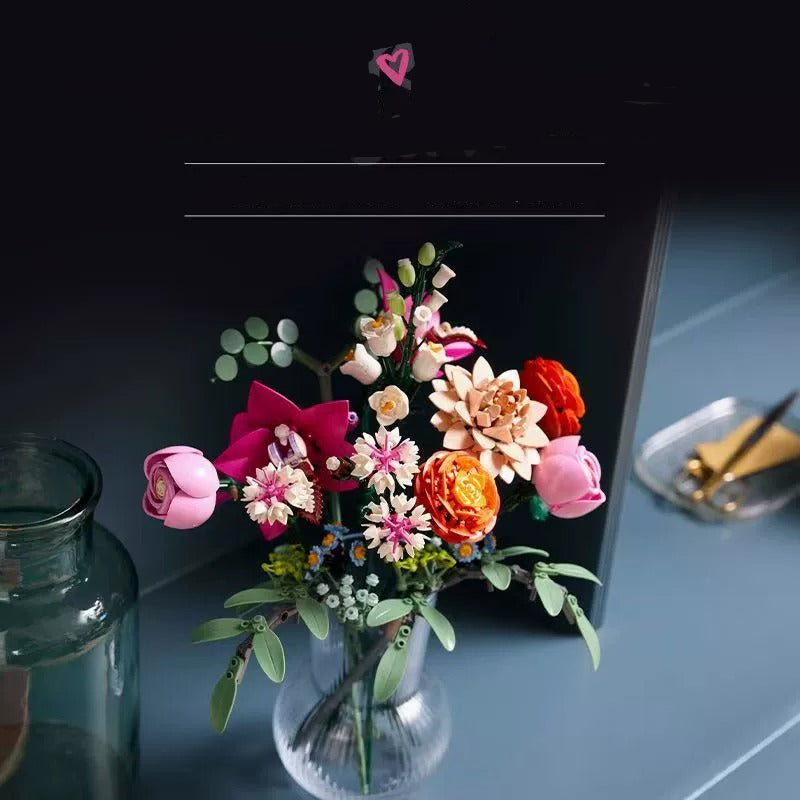 Colorful flower bouquet in a clear vase on a reflective surface with text in the background