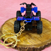 Toy ATV keychain on a wooden stand with a pink background