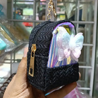 Black textured keychain pouch with a butterfly design held in front of a store interior.