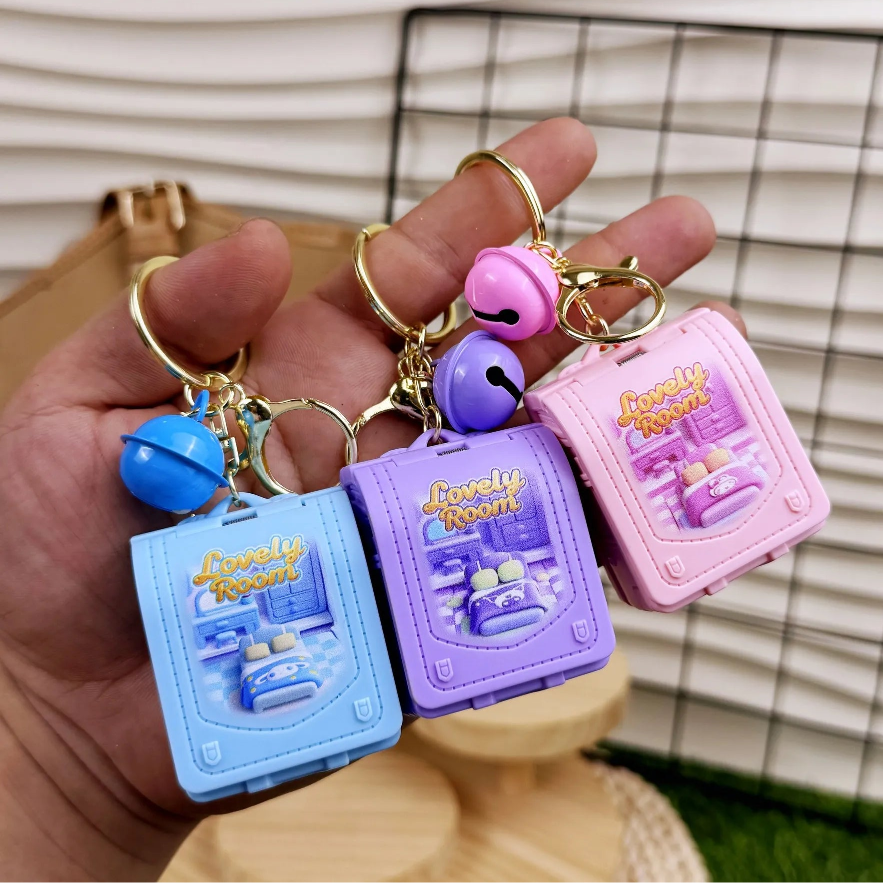 Three colorful keychains held in a hand with a checkered background
