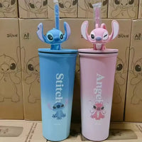 Two cartoon-themed cups, one blue with 'Stitch' and one pink with 'Angel', in front of boxes featuring cartoon characters.