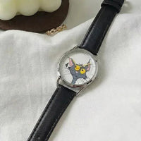 Wristwatch with a cat face design on the dial, black leather strap, on a white fabric background