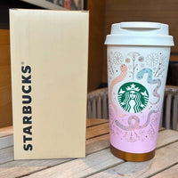 Starbucks tumbler with pink design and wooden box on a wooden surface
