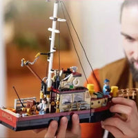 Person holding a detailed model ship with text in the background