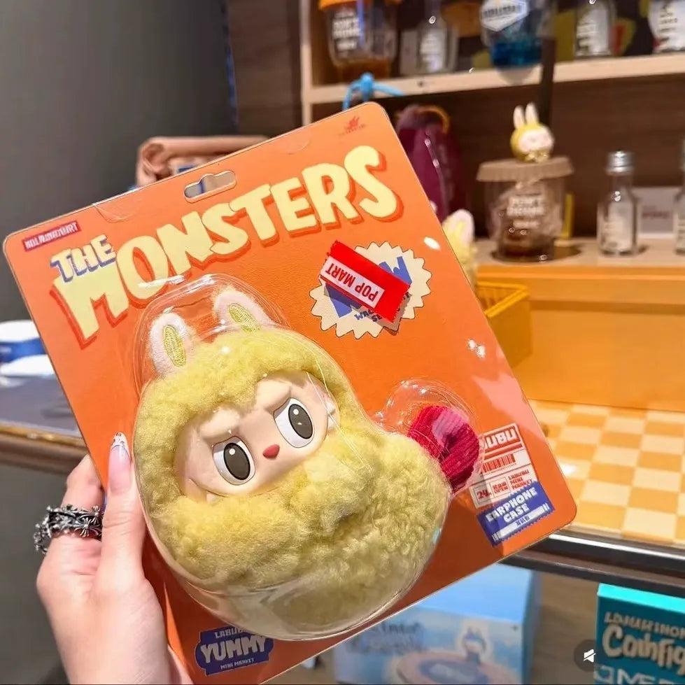 Toy figure in packaging with 'The Monsters' branding held by a person.