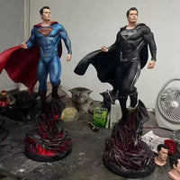 Two superman statues on stands with a plain background