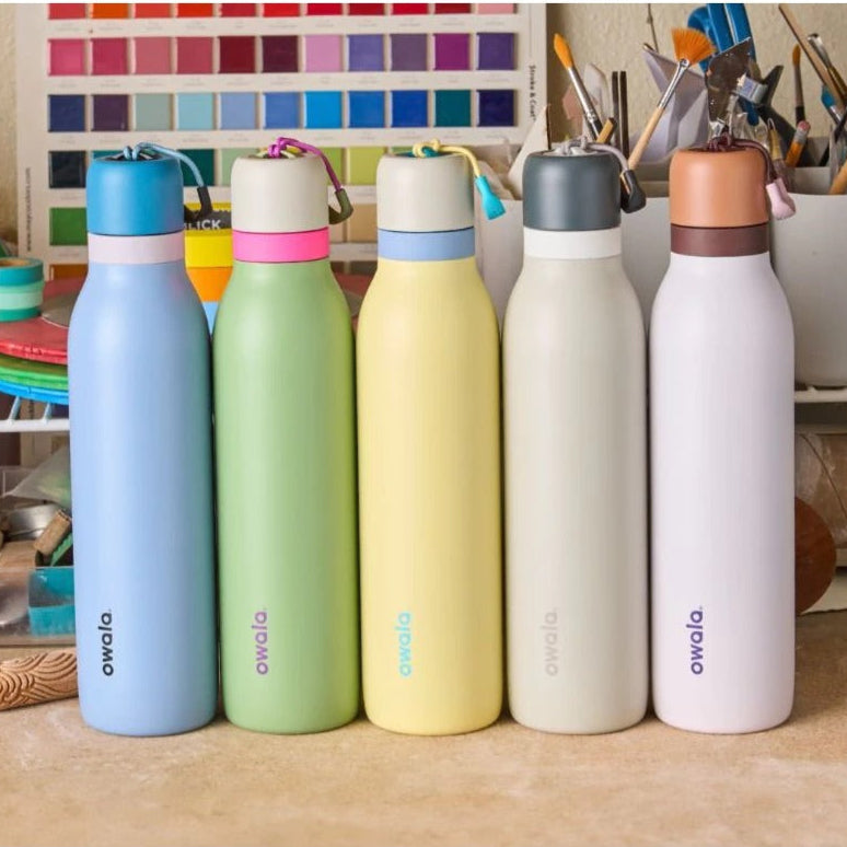 Five colorful water bottles with 'owala' branding on a wooden surface.