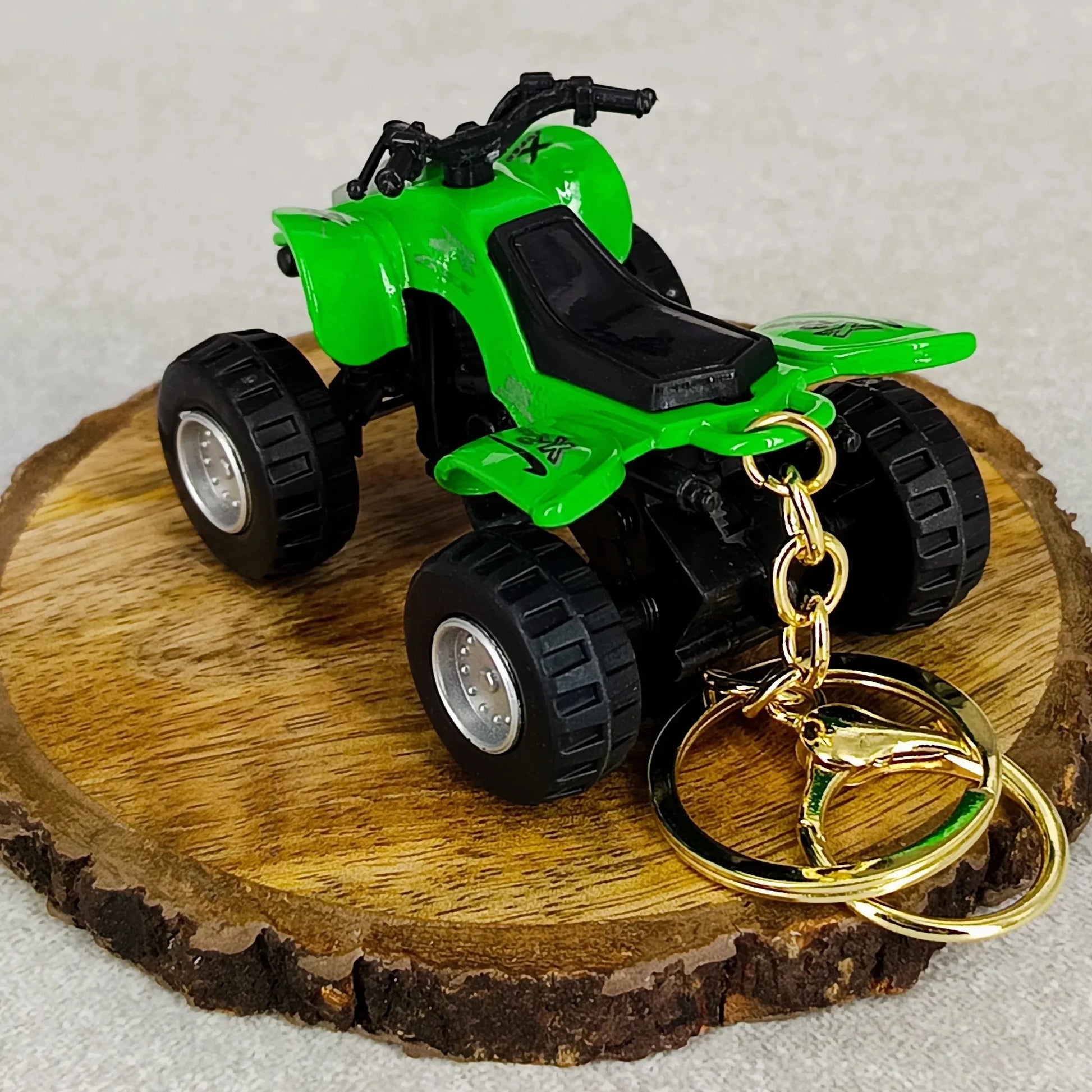 Green toy ATV on a wooden disc with gold keychain