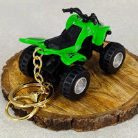 Green toy ATV on a wooden slice with gold keychain