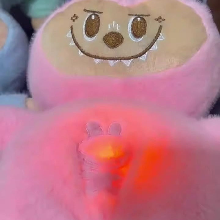 Pink plush toy with cartoon face and glowing red light on a dark background