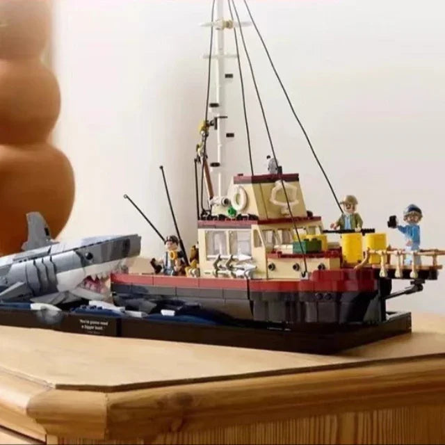 Model ship and shark on a wooden surface with decorative elements in the background