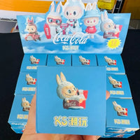 Display of Coca-Cola themed KS cartoon character boxes held by a hand.