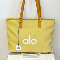 Yellow tote bag with 'alo' branding on a white background