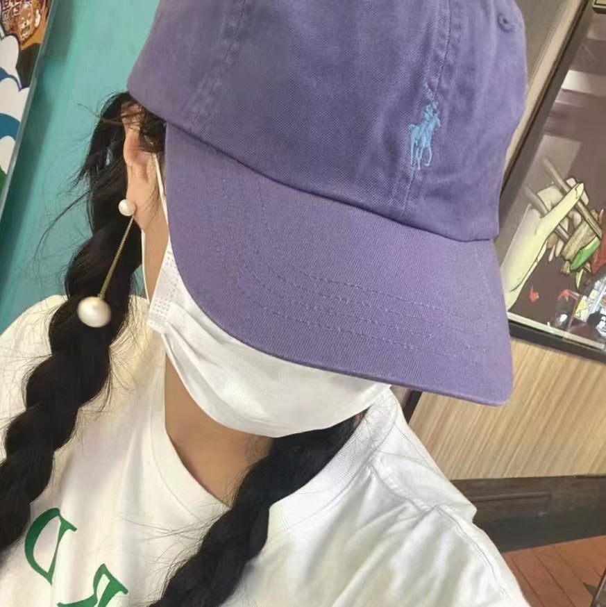 Person wearing a purple cap and white face mask with green text on a blurred background