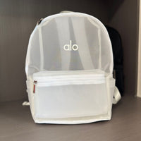 Clear backpack with 'alo' branding on a gray surface