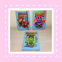 Three superhero-themed notebooks with Iron Man, Spider-Man, and Thanos on a pink border.