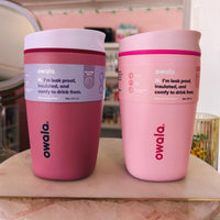 Two pink Owala tumblers on a marble surface with a blurred store background.