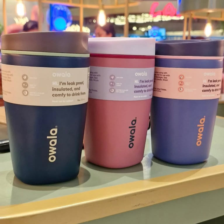 Three owala insulated tumblers on a shelf with a blurred indoor background