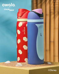 Two Owala water bottles, one red with shell pattern and one blue with character design, on a sandy surface.