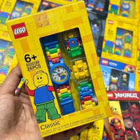 LEGO watch set packaging held by a hand with more LEGO sets in the background