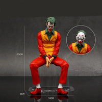 Joker figurine with green hair and clown makeup on a gray background