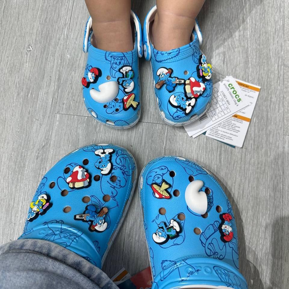 Blue children's crocs with smurfs character design on a gray floor