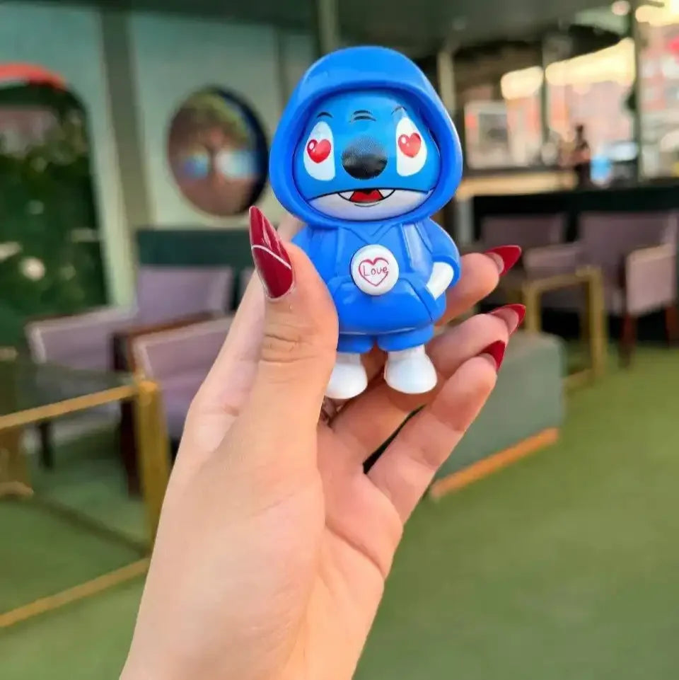 Hand holding a blue cartoon character figurine in an indoor setting