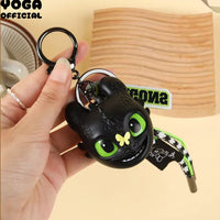 Black and green keychain held by a hand with a wooden surface in the background