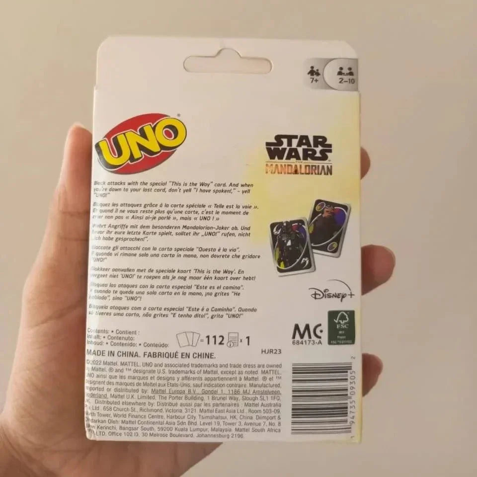 Hand holding a UNO card game packaging with Star Wars and Disney branding on a beige background