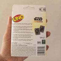 Hand holding a UNO card game packaging with Star Wars and Disney branding on a beige background