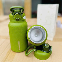 Green Starbucks insulated tumbler with a lid on a wooden surface.