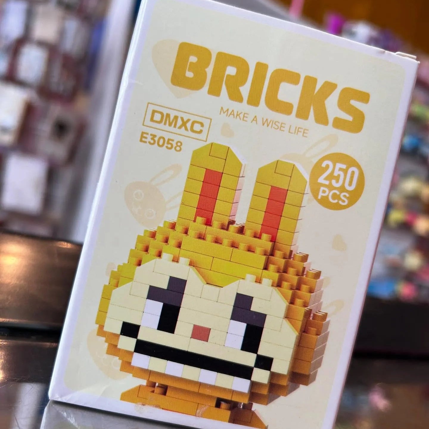 Box of DMXC Bricks with a pixelated character design on a blurred background