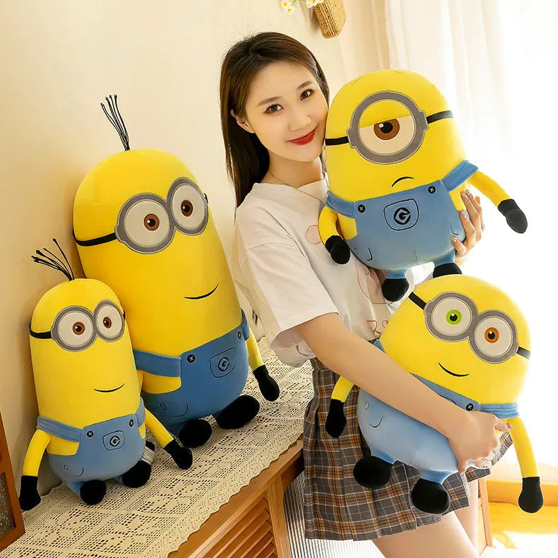 Woman holding a large plush minion toy with three other plush minions on a table.