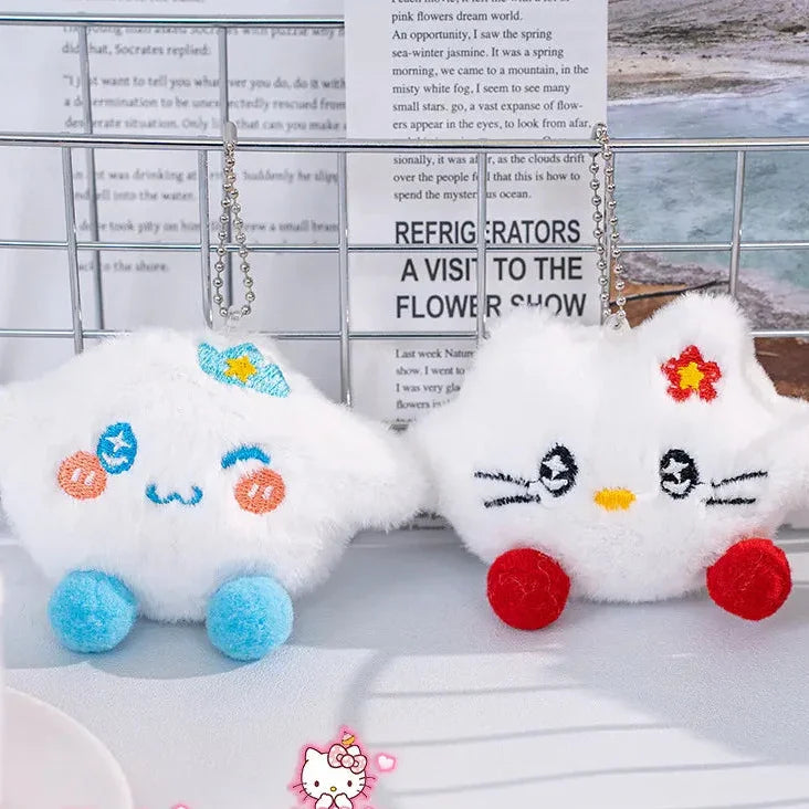 Two plush toys with cartoon faces on a surface with a magazine in the background, featuring the Hello Kitty brand.