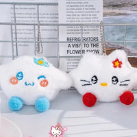 Two plush toys with cartoon faces on a surface with a magazine in the background, featuring the Hello Kitty brand.