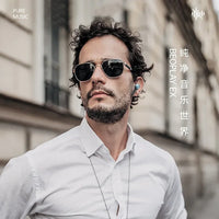 Man wearing sunglasses and a white shirt with text and branding elements.